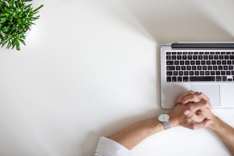 Hands clasped together on a laptop from above