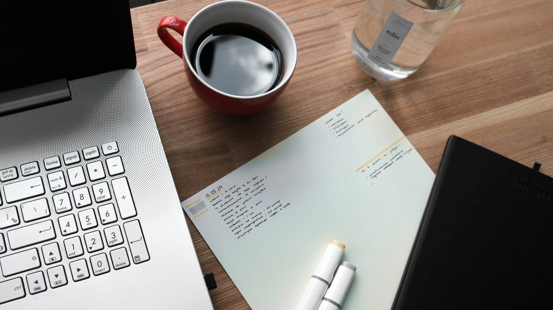 A laptop, written notes, and coffee mug on a wooden table