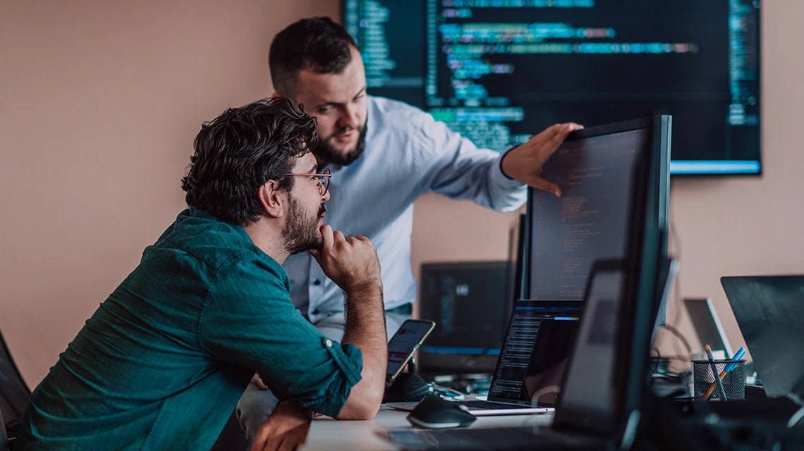 Deux personnes qui discutent devant un écran d'ordinateur que l'une d'elles est en train de montrer. | Klaxoon