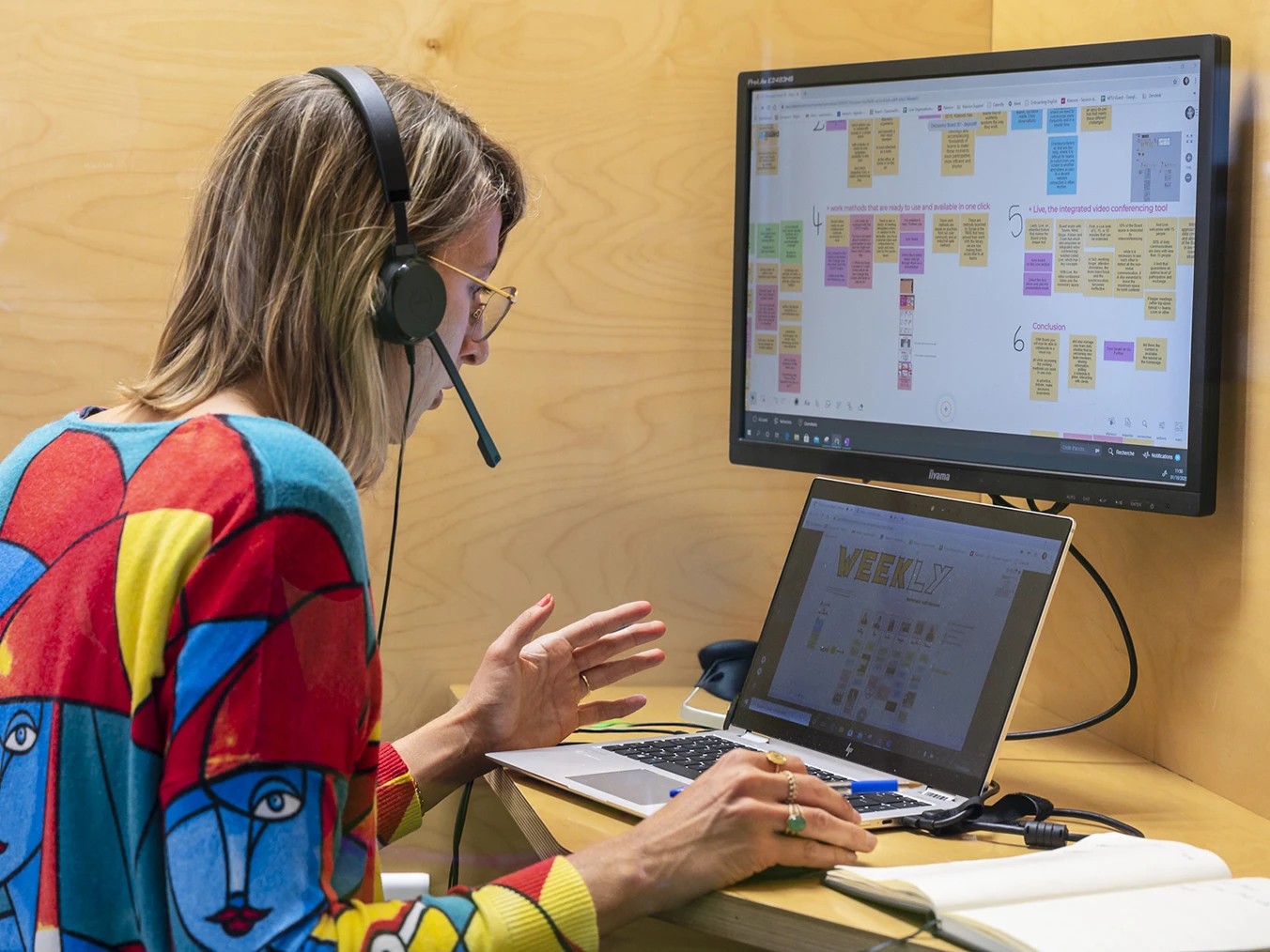 Two support experts wearing headsets collaborating at computers.