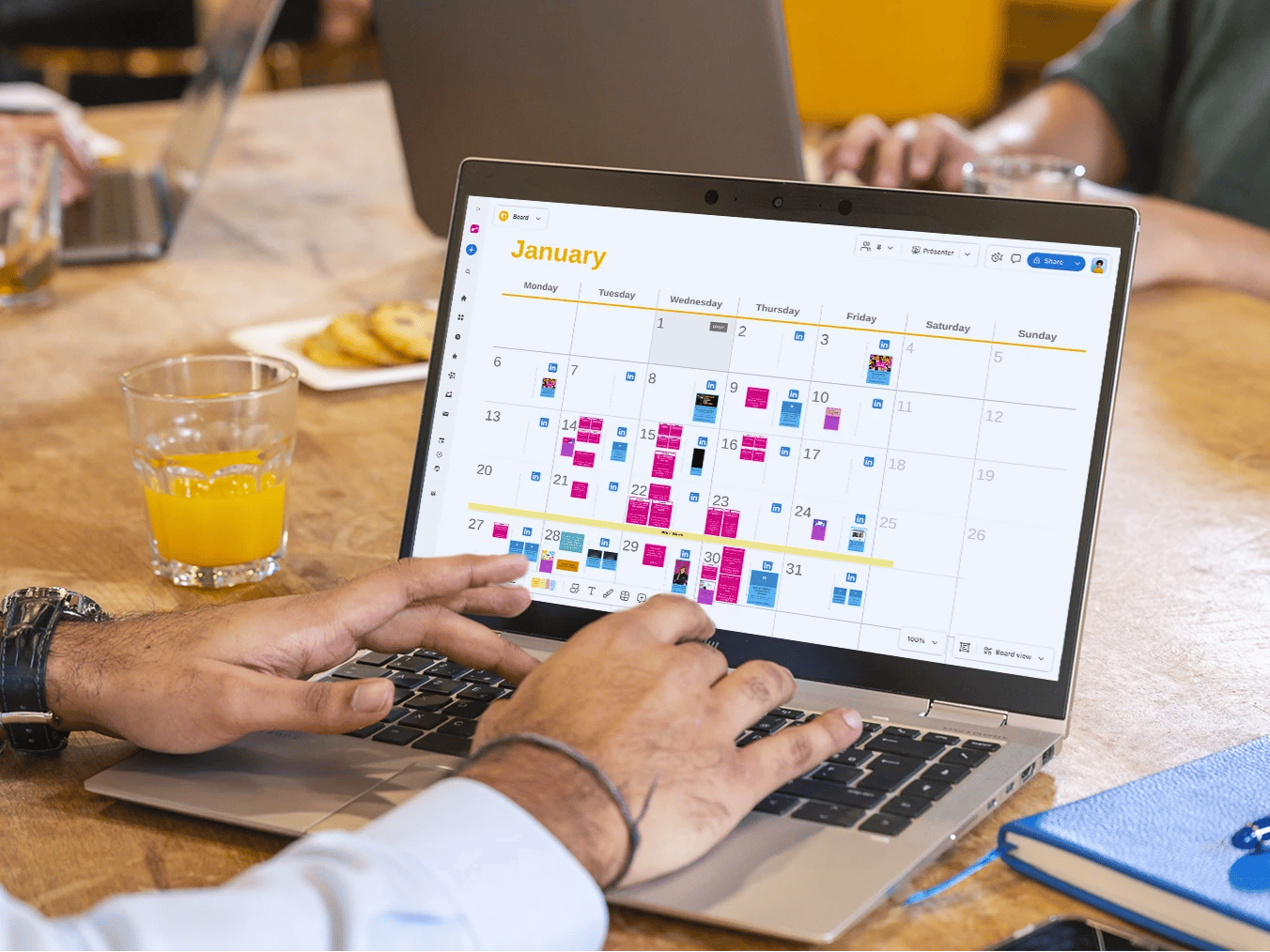 Team collaborating on content production with laptop, notes and smartphones around a table.