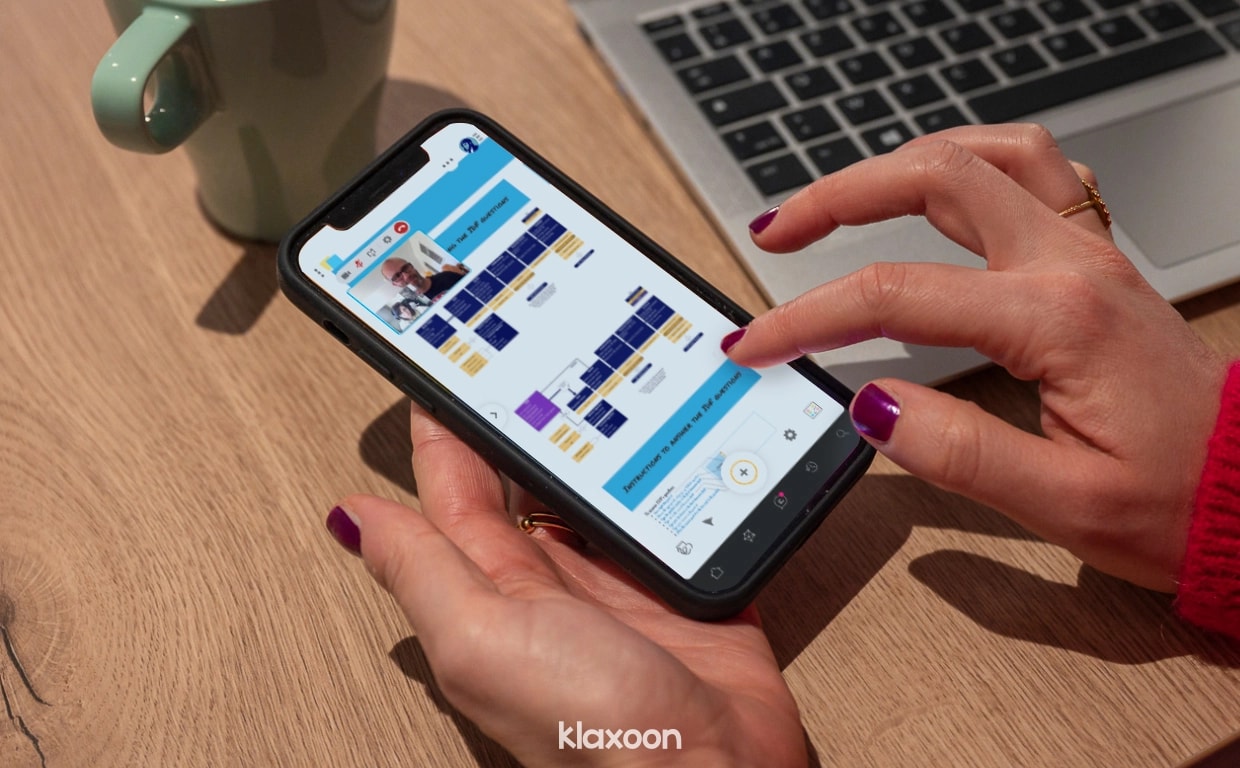 A person working remotely on their mobile, answering the questions asked on the Board shared by Valérie during the workshop. | Klaxoon