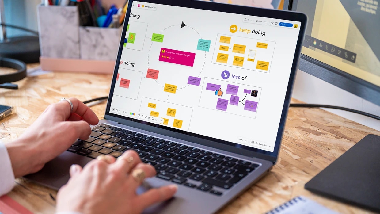 A person working on a computer displaying a team retrospective template on a Board. | Klaxoon