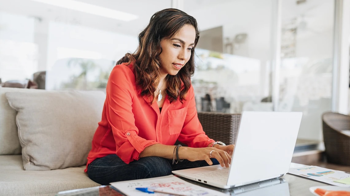 Une personne travaillant sur un ordinateur posé sur une table basse. | Klaxoon