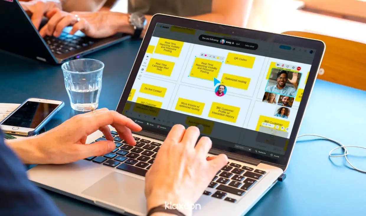 Une personne en visioconférence sur ordinateur, avec d’autres participants connectés via Live sur un Board, et l’un d’entre eux qui a pris la synchro. | Klaxoon