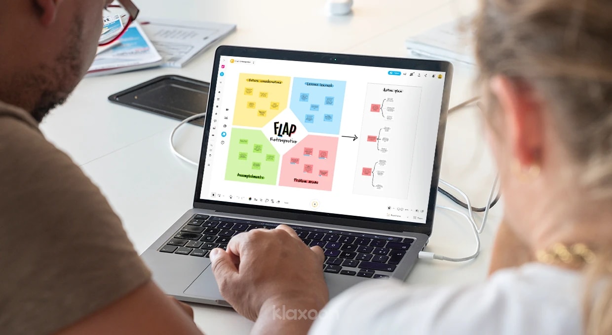 Two people working on a computer displaying a FLAP Retrospective Board. | Klaxoon