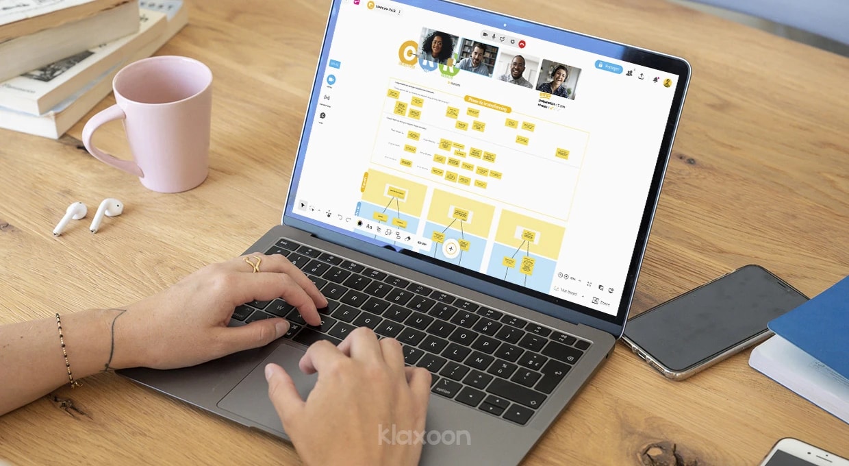 Une personne qui travaille sur un ordinateur qui affiche un Board structuré d’après la méthode OKR, ainsi que d’autres personnes connectées en visio. | Klaxoon