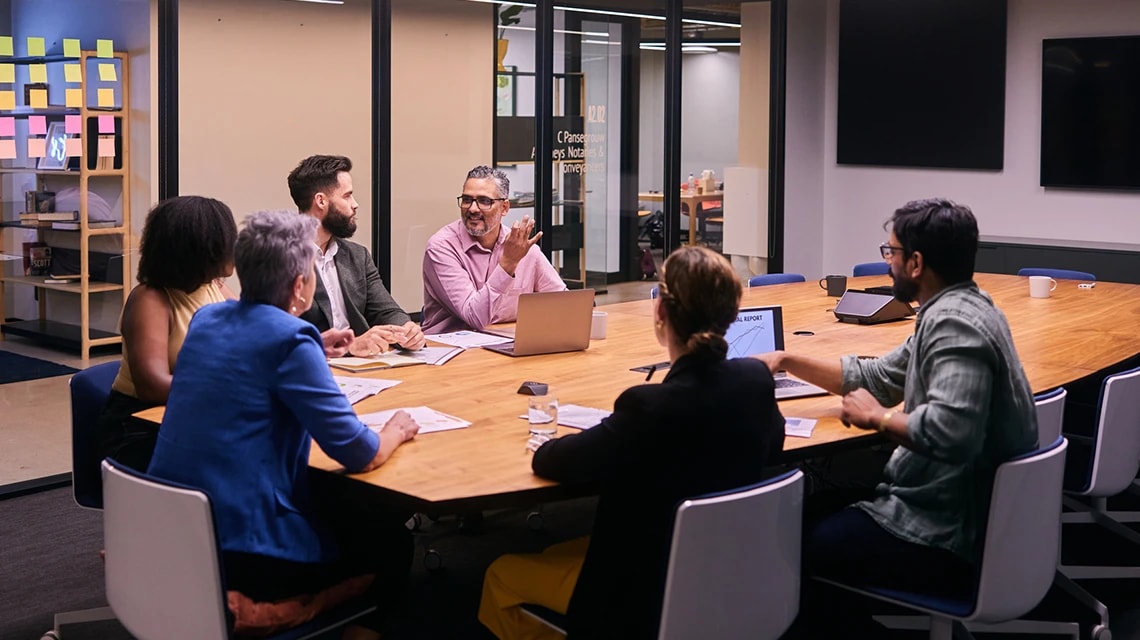 Équipe travaillant sur des ordinateurs dans une salle de réunion pour un kick-off meeting collaboratif. | Klaxoon