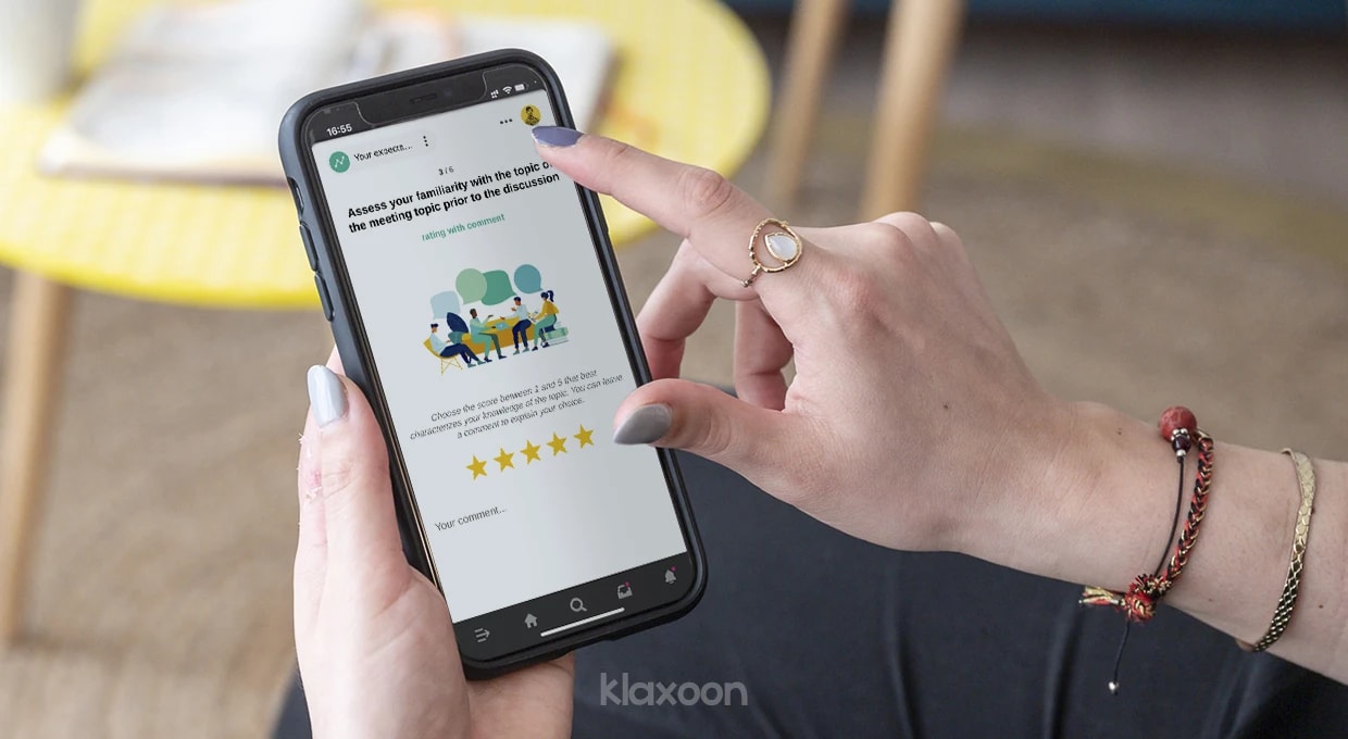 A person who fills in their expectations before the meeting in the survey on their mobile phone. | Klaxoon