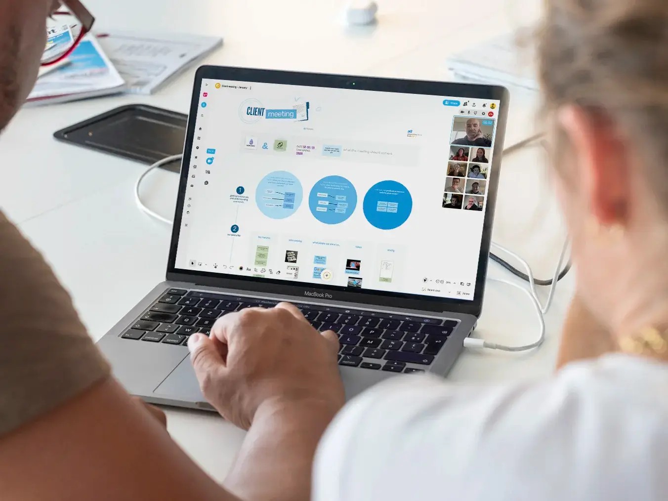 Klaxoon sales team collaborating with Wrike dashboards on laptops around a meeting table.