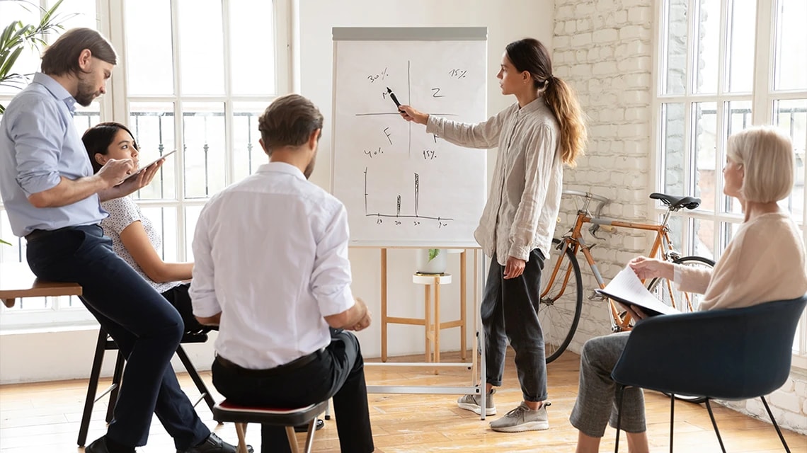Plusieurs personnes réunies autour d'un tableau blanc dans le cadre d'un projet transverse. | Klaxoon