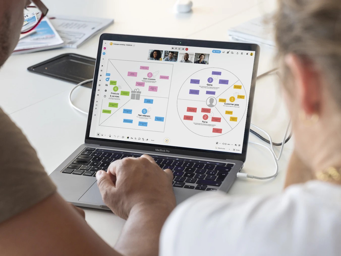Two people working on a computer displaying a brainstorming session on the value proposition of a marketing campaign. | Klaxoon