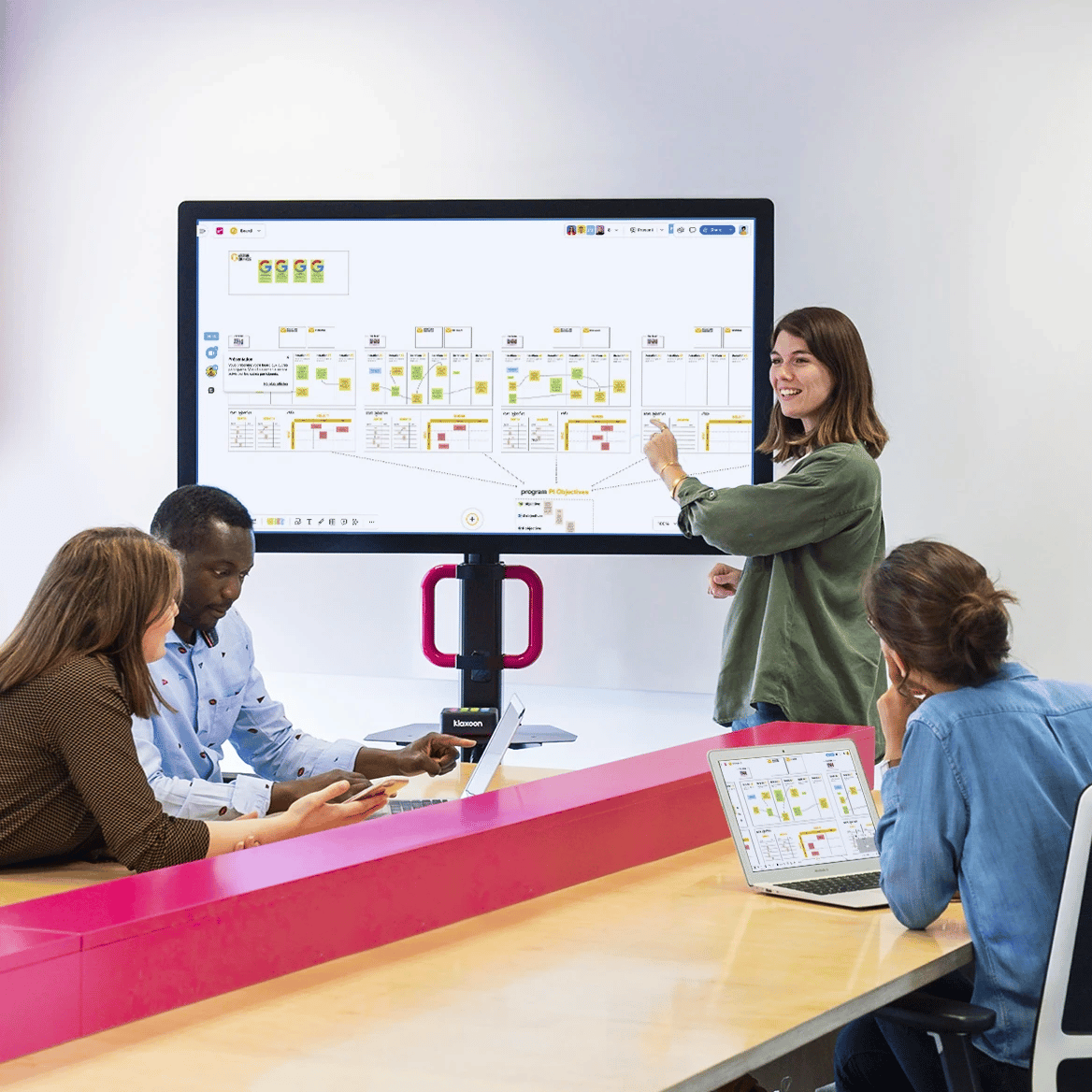 Équipe agile en réunion debout devant un tableau de post-it colorés.