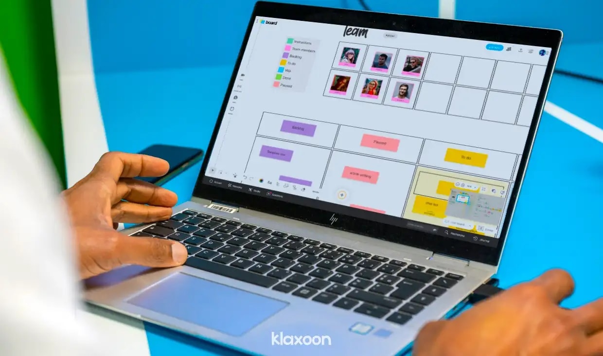A person working at a computer displaying a Board with photos of team members and color-coded ideas. | Klaxoon