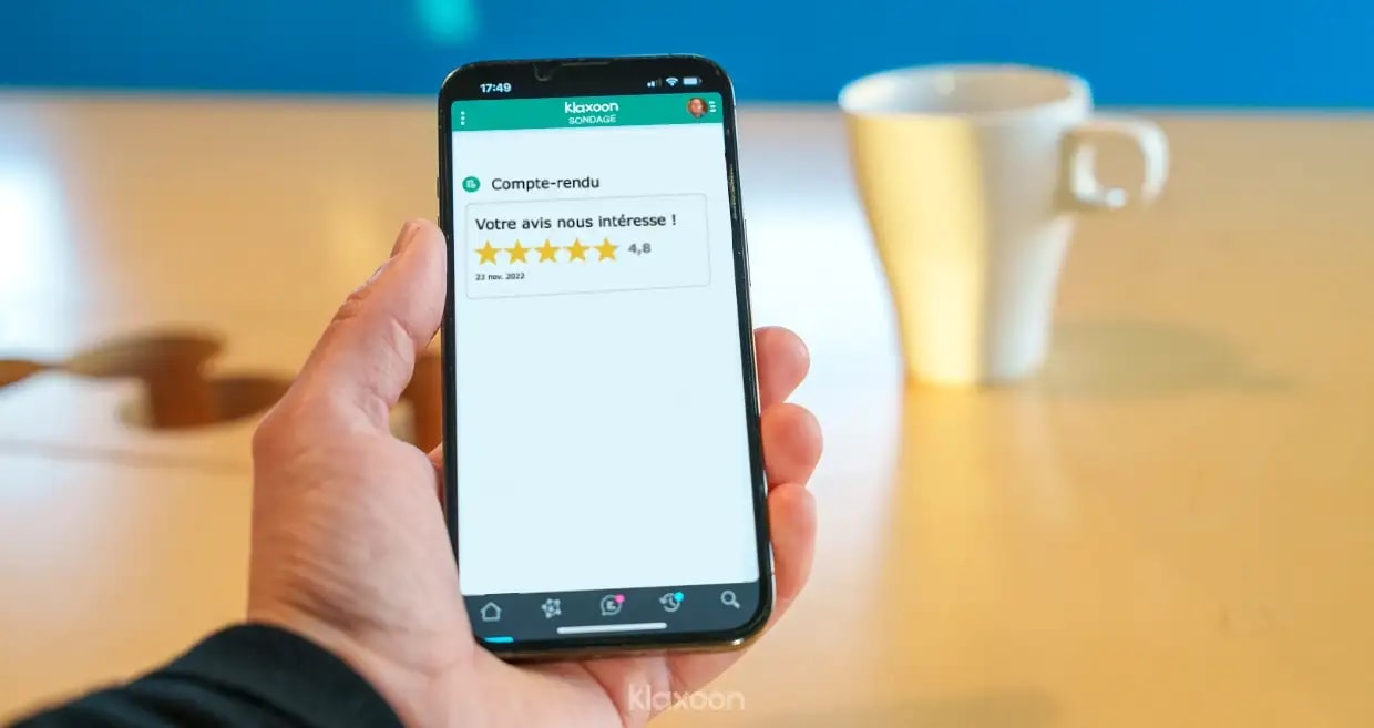 A person holding a phone that displays a Survey’s results with a rating of 4.8/5. | Klaxoon