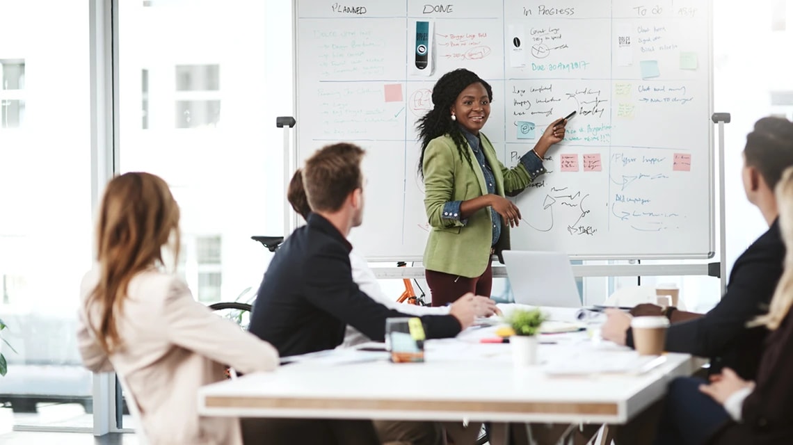 Plusieurs personnes en réunion autour d'un tableau blanc physique. | Klaxoon