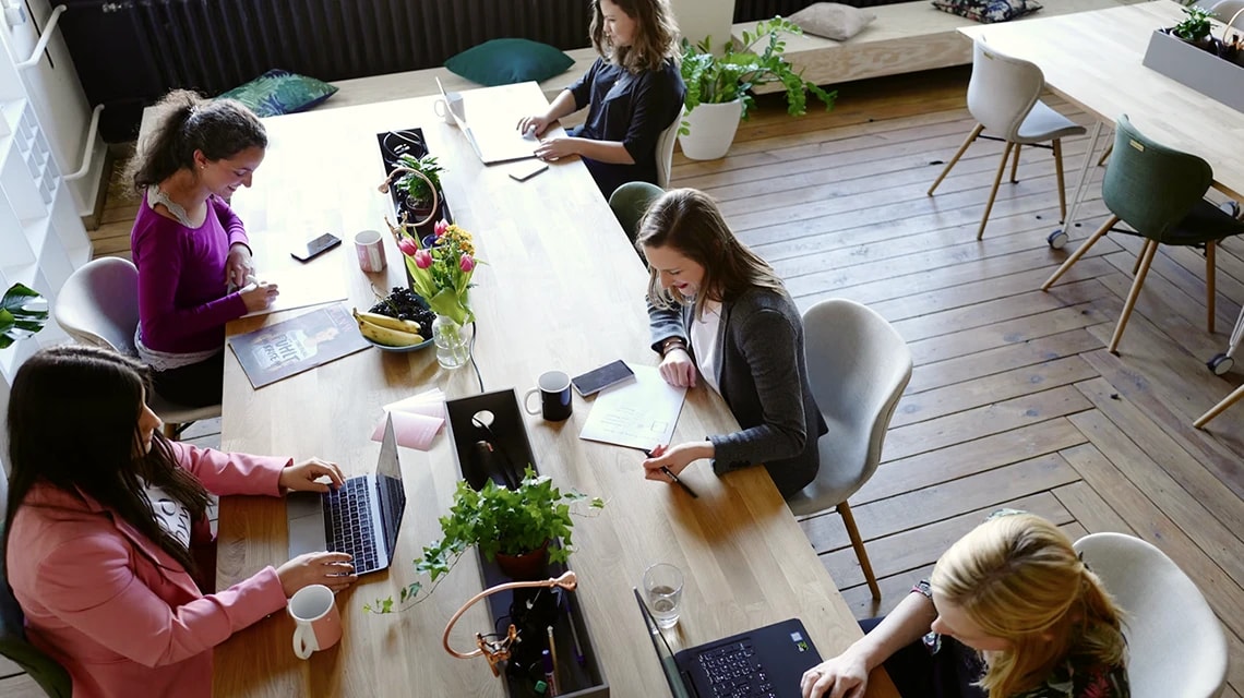 Une équipe en réunion autour d'une table avec des écrans et des smartphones. | Klaxoon