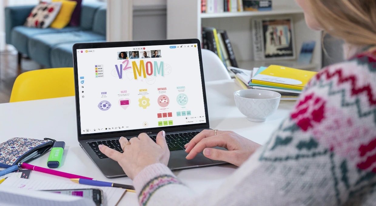 A person working on a desktop displaying a Board with the V2MOM template and a team connected via video conference. | Klaxoon