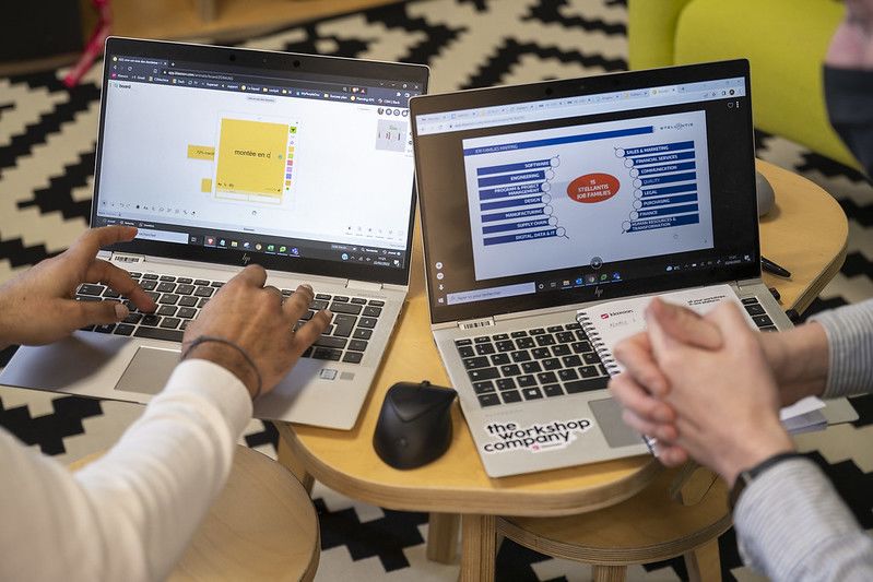 Deux ordinateurs portables posés côte à côte sur une table, affichant des notes prises par des collaborateurs. | Klaxoon