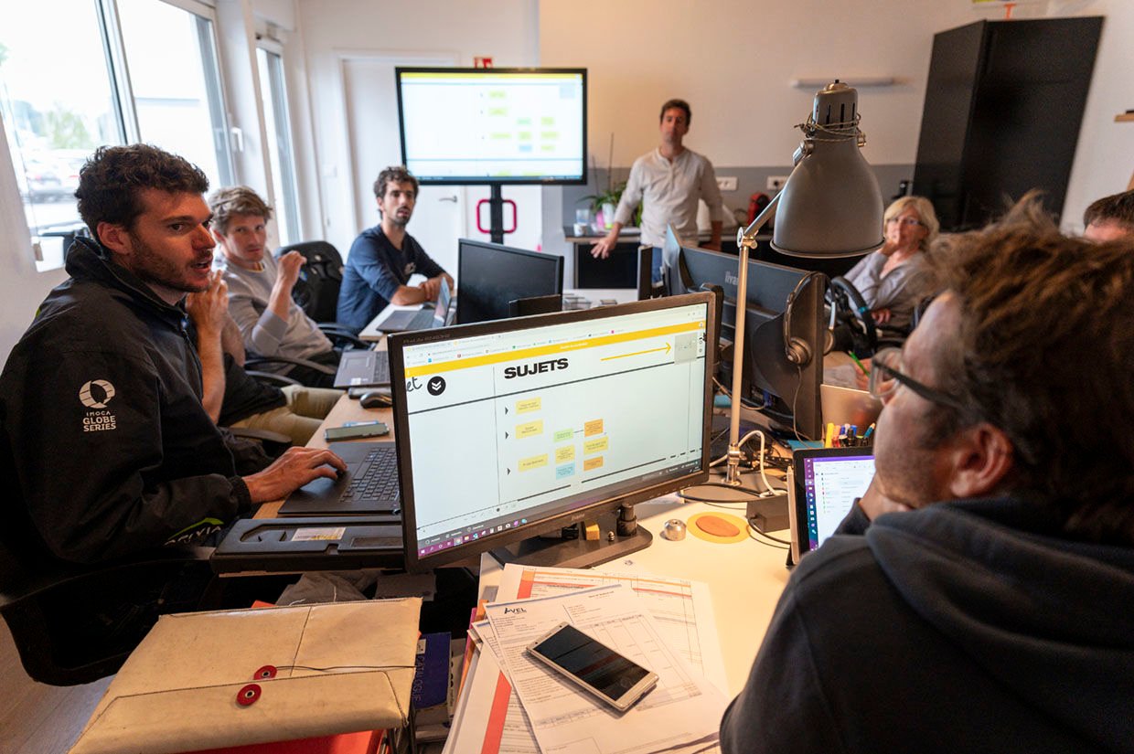 The MerConcept team discussing in front of several screens displaying Boards. | Klaxoon