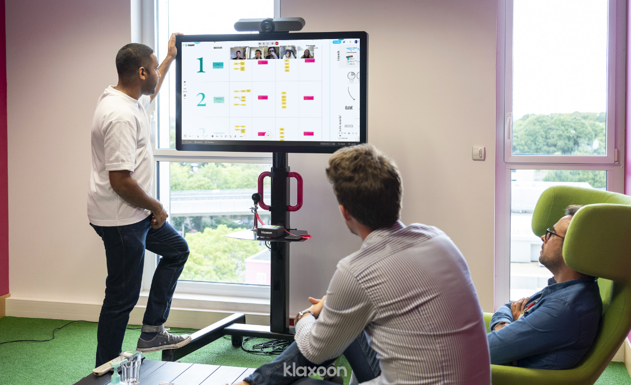 Trois personnes sont réunies autour d’un écran sur lequel Board leur permet de travailler avec leurs collègues à distance. Ensemble, ils complètent la matrice McKinsey grâce au modèle prêt à l’emploi. | Klaxoon