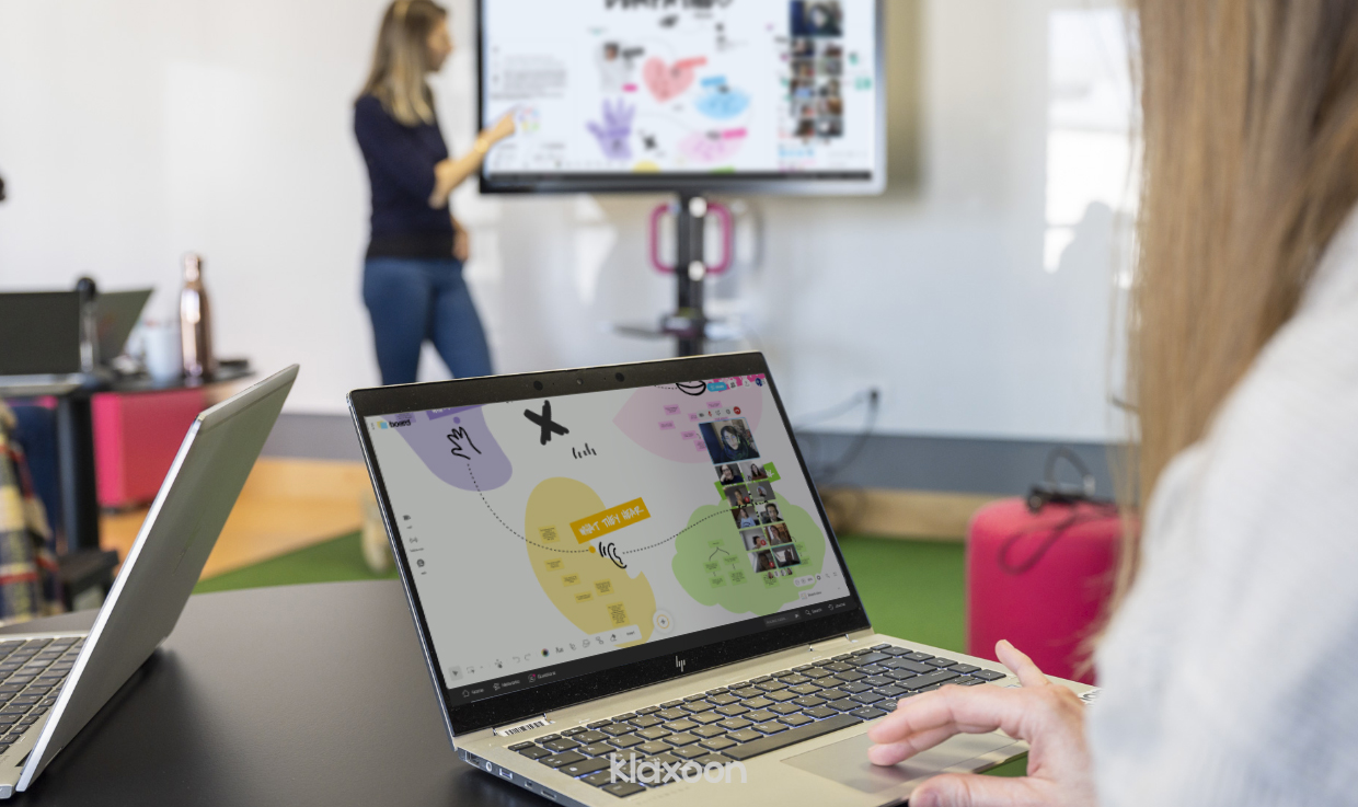 A team in the middle of creating an empathy map. Some people are gathered in a room, around screens showing the Board; others participate through videoconferencing. | Klaxoon