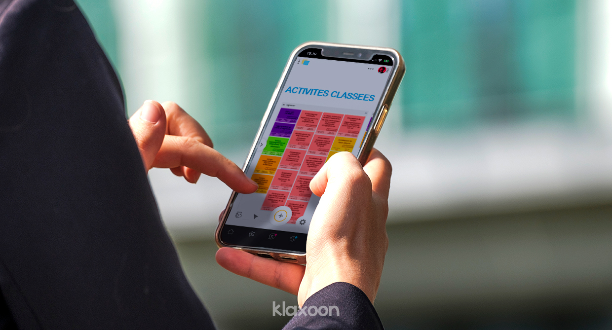 Une personne travaillant sur mobile, avec un Board de suivi d'activités ouvert, où les idées sont disposées en colonnes. | Klaxoon