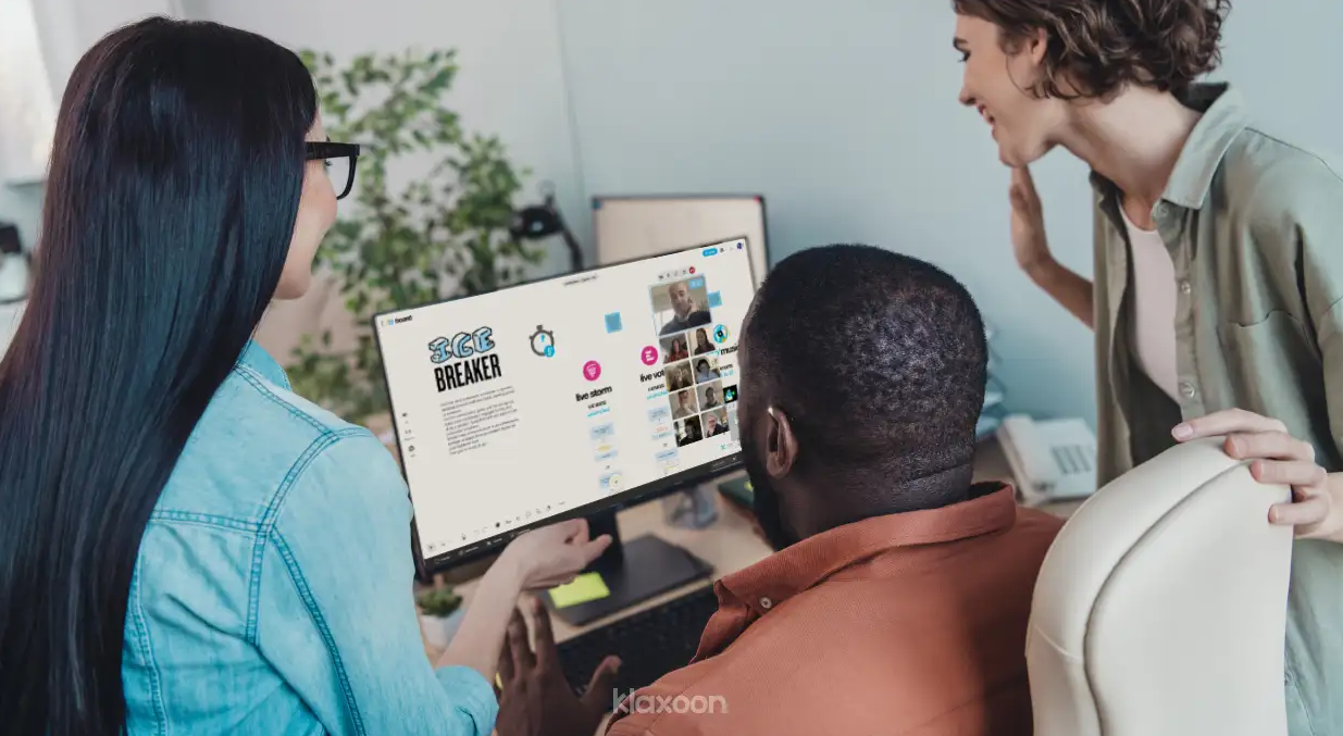 Three people doing an ice breaker with their team on a laptop, with the rest of the team joining remotely via Board. | Klaxoon